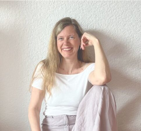 Angelika Kunjan lädt ein zum Frauenseminar Angelika Kunjan sitzt lächelnd an der Wand.